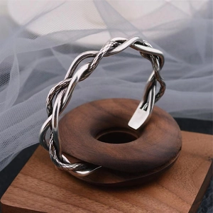 Vintage Thai silver twisted braid open bangle on wooden display stand with soft backdrop