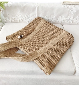 Detailed close-up of straw woven tote bag texture with fringe and wooden beads