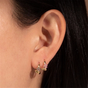 Detalle de pendientes de flores doradas con gemas de colores usados en la oreja