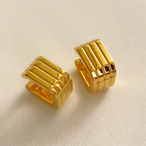 Macro shot of gold square hoop earrings with textured vertical ridges and metallic finish