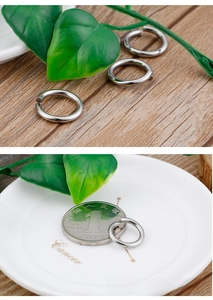 Macro shot of silver stainless steel jump rings on a white plate with coin for size reference