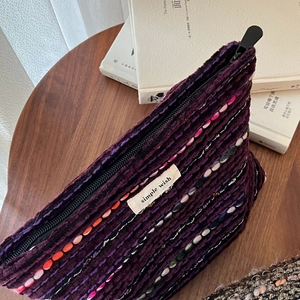 Close-up of vintage purple tweed makeup bag with woven patterns on a wooden table