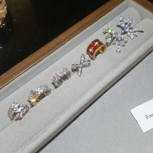 Macro detail of various zircon bow ear cuffs and rings on gray velvet display tray