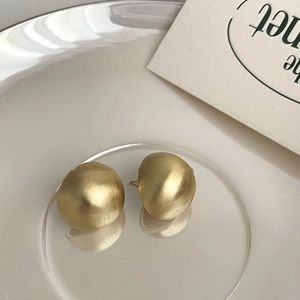 Elegant gold matte dome earrings with a brushed metallic finish on a textured background