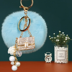 Detail of light blue faux fur keychain with rhinestone mini bag and pearl charms