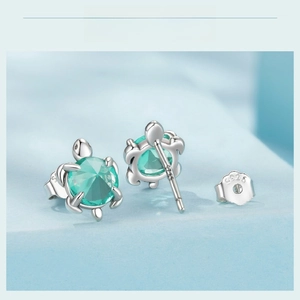 Macro shot of S925 sterling silver sea turtle stud earrings with green zircon stones
