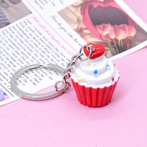 Close-up of a realistic cupcake keychain with a red heart and colorful sprinkles on top