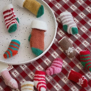 Macro shot of knitted Christmas mini socks in various festive colors and patterns on a tray