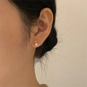 Close-up detail of a minimalist 925 silver rabbit pearl stud earring on a model ear