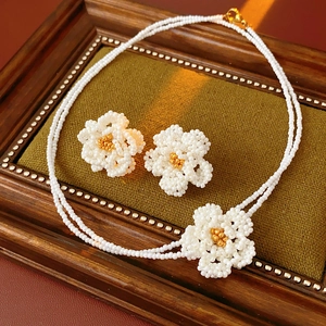 Detail of handmade double-layer white bead necklace and flower earrings on vintage display
