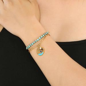 Detail of layered gold bracelet featuring turquoise beads and palm tree dolphin charms