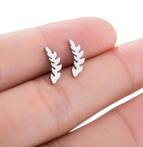 Close-up of matte silver leaf-shaped stainless steel stud earrings held in hand
