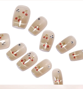 Détails des faux ongles œil-de-chat champagne avec motifs cerises rouges et petits strass