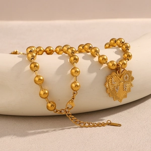 Dettaglio macro della collana a sfere placcata oro 18K con ciondolo a cuore e cristalli