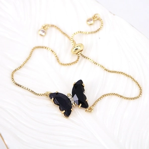 Detail of adjustable gold chain bracelet with a black butterfly pendant and zircons