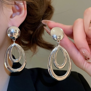 Gros plan de boucles d'oreilles goutte argentées polies sur un modèle montrant la taille