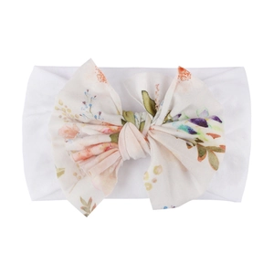 Détail d'un bandeau pour bébé en nylon avec un grand nœud à imprimé floral coloré