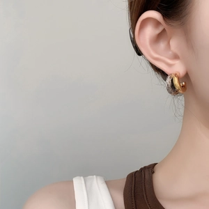 Nahaufnahme der zweifarbigen gedrehten C-Ohrringe in Gold und Silber an einem Modell