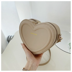 Dettaglio della borsa a tracolla beige a forma di cuore con scritte dorate e cinturino