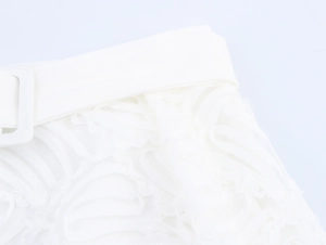 Détail de la taille d'une jupe en dentelle blanche avec tissu texturé et boucle carrée