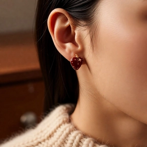 Close-up of 18K gold plated strawberry earrings with red enamel and star details