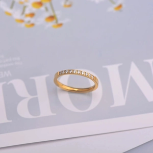 Macro di un anello eternity dorato minimalista con cristalli trasparenti su una rivista