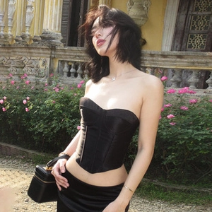 Detail of elegant black satin corset top featuring a luxurious glossy finish outdoors