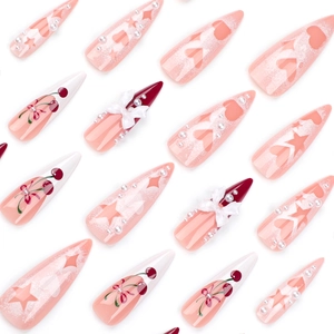 Pink stiletto press-on nails with 3D bows, cherry patterns, and heart accents