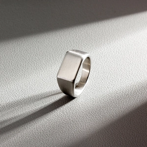 Macro shot of silver minimalist titanium steel ring with a brushed matte finish and rectangular face