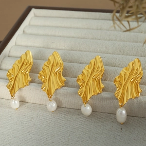 Elegant gold diamond-shaped earrings with freshwater pearls on a velvet display