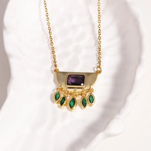 Detailed close-up of a vintage gold necklace with purple gemstone and green teardrop tassels