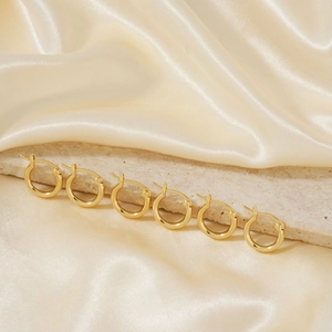 Minimalist gold geometric hoop earrings set for women on champagne silk background