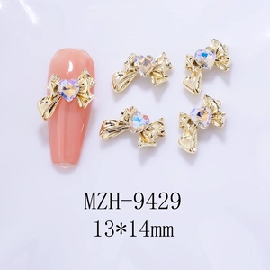 Detailed view of 13x14mm golden bow nail charms with AB aurora heart rhinestones
