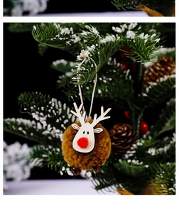 Detail of a brown felt reindeer ornament with red nose and bell on a snowy Christmas tree