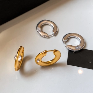 Gold and silver chunky hoop earrings with marquise-cut zircon stones on white background
