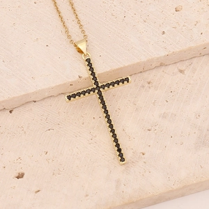 Elegant gold cross pendant necklace with black zircon inlay on natural stone background