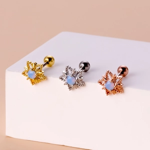 Detailed view of three snowflake stud earrings in gold silver and rose gold finishes