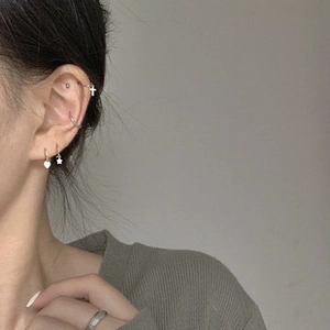Close-up of S925 sterling silver heart and cross pendant earrings on model ear