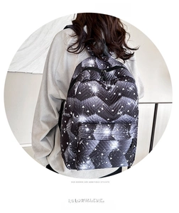 Vista trasera de una mochila negra con patrones de corazones y estrellas usada por modelo