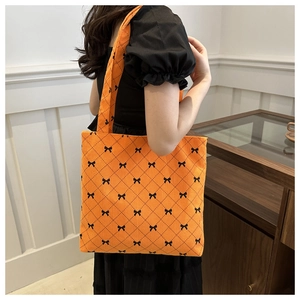Detailed view of an orange corduroy tote bag with black bow tie diamond patterns