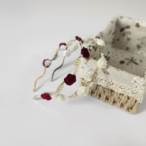 Detailed view of floral headbands with red roses, white roses, and pearl accents