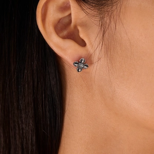 Close-up of model wearing punk style stainless steel cross stud earrings in retro silver