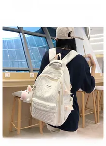 Détail d'un sac à dos blanc à texture bulles avec pendentif lapin en peluche et fermetures