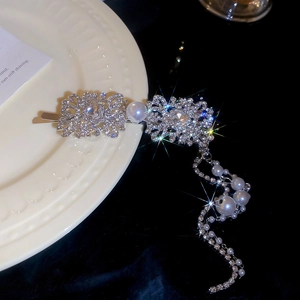Detailed close-up of a silver hair clip with tassel pearls and sparkling rhinestones