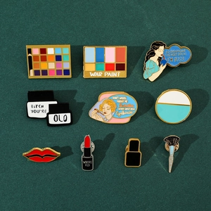 Detailed flat lay of creative makeup-themed enamel pins featuring colorful eyeshadow palettes