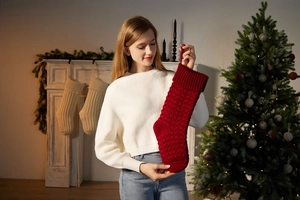 Macro detail of classic red cable knit Christmas stocking hanging by a fireplace