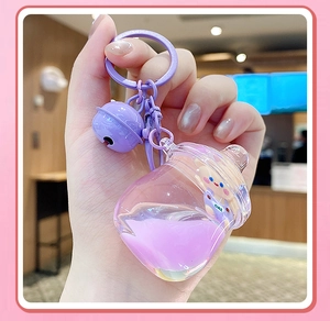 Détail du porte-clés ours avec liquide violet tenu en main pour voir la taille