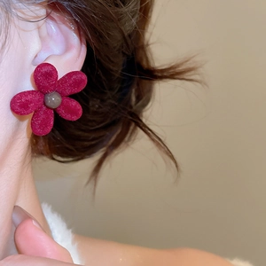 Macro view of a red flocked flower stud earring featuring a soft velvet texture