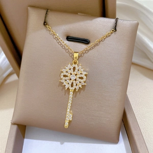 Detail of gold hollow flower key pendant with sparkling pavé zircons on silk background
