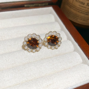 Macro detail of amber gemstone and white pearl flower earrings in a velvet gift box